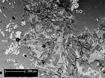 Figure 2d Scanning electron microscope image of sample 1965411, showing a zone of sericite–chlorite alteration, which overprints the primary igneous texture of the rock. Abbreviations: bt, biotite; chl, chlorite; Ksp, K-feldspar; mu, muscovite; plag, plagioclase; qtz, quartz; ser, sericite; TiO, titanium oxide (leucoxene). (Photo 415925)