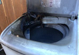 Photo showing an example of an electrical product failure. It shows a damaged washing machine.