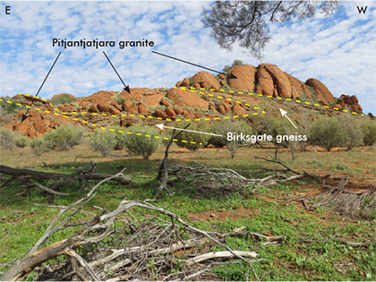 Figure 2 Northern side of Wallaby Rock showing the gently west-dipping Birksgate Complex gneiss megaraft within Pitjantjatjara Supersuite granite. In the central-eastern part of the photo, the gneiss megaraft is split into an upper and lower layer by a lenticular granite intrusion. (Photo 415775)