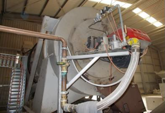 Photo showing a preowned resin sand dryer (Type B appliance) undergoing modifications and installation. It is a large silver appliance with pipes attached.